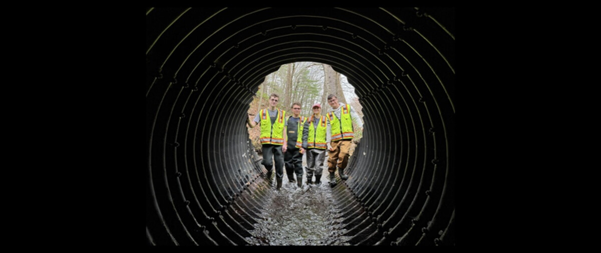 McTaggarts-dam-project-hero-1 WPI students looking through a stream culvert